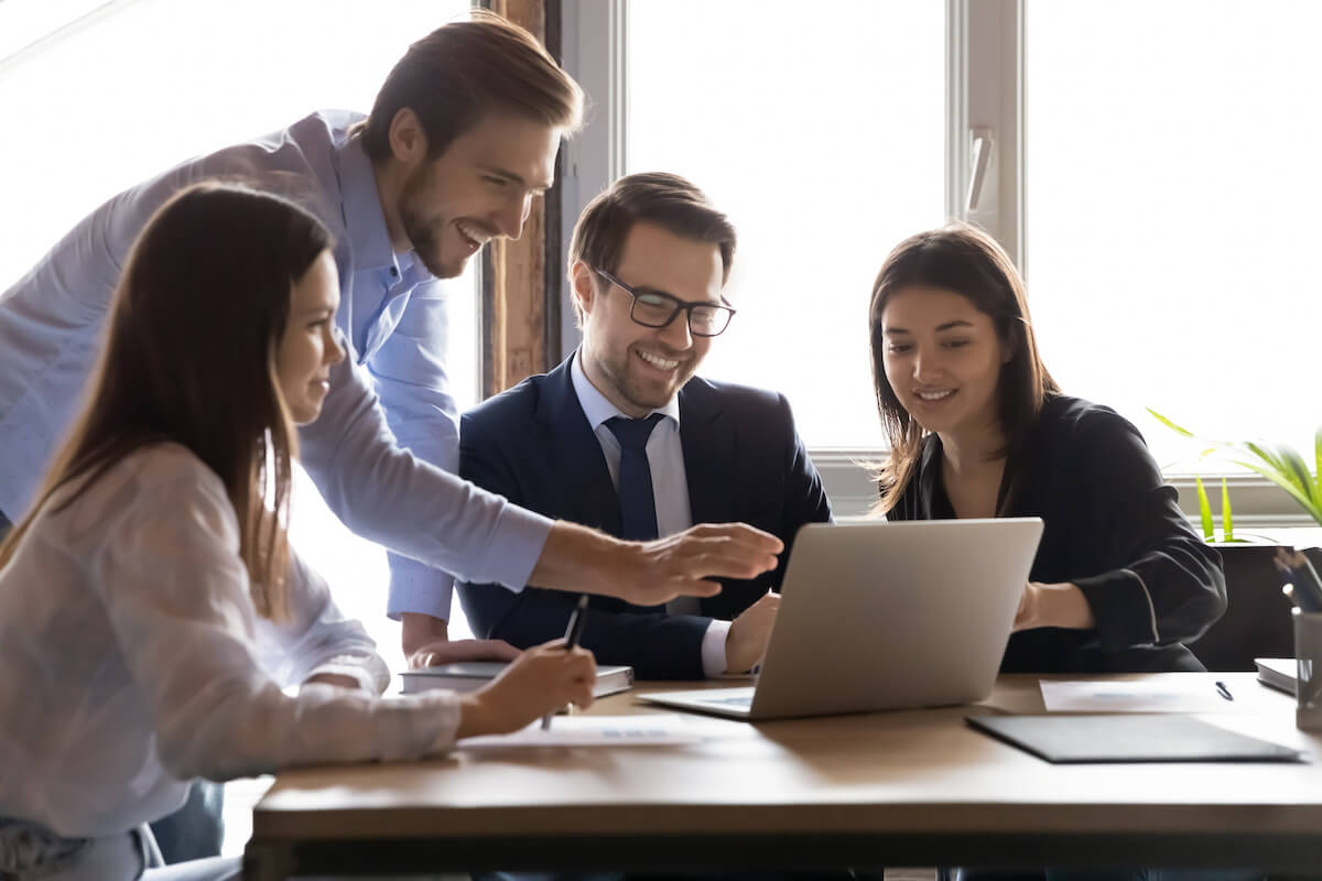 Top human capital management software: team happily looking at something on a laptop