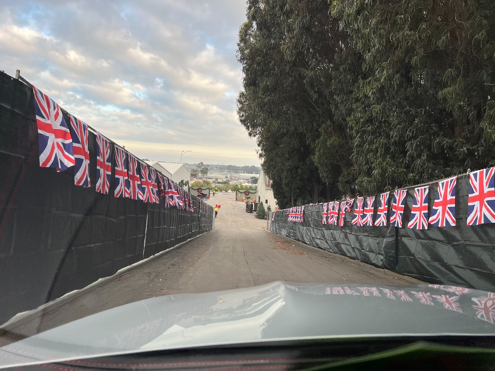 A downward sloped road is lined with British flags. 