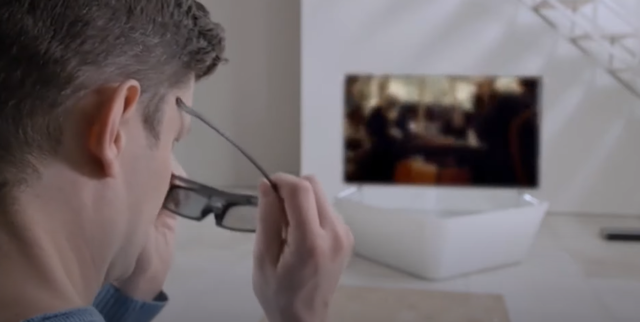 A man wearing 3D glasses while watching TV