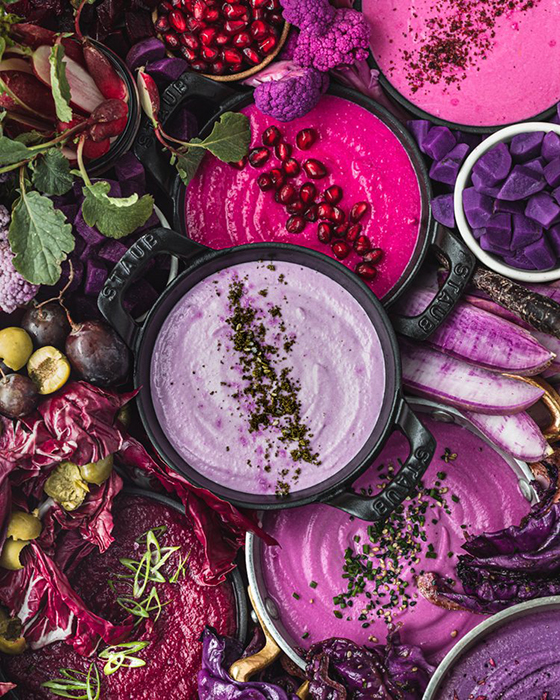 Staub cast irons full of pink and purple yogurts, surrounded by green produce. food photography by Daniela Gerson 