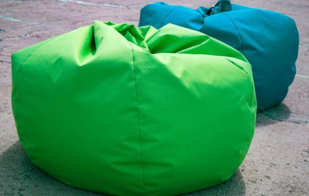 Two bag chairs, green and blue, on the open air resting on the stone pavement. Selective focus. Stuf for sea vacation, leisure and tourism. Two bag chairs, green and blue, on the open air resting on the stone pavement. Selective focus. Stuf for sea vacation, leisure and tourism. outdoor beanbags stock pictures, royalty-free photos & images