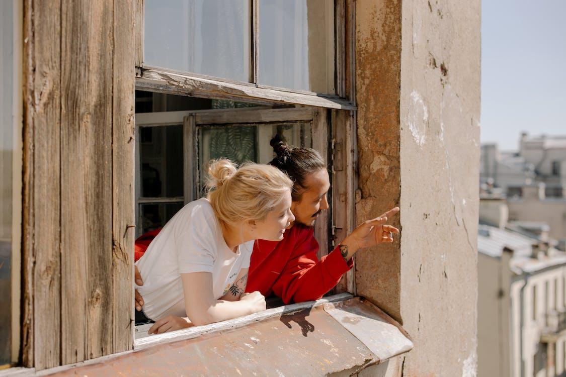 Free Woman in White Shirt and Red Pants Sitting on Window Stock Photo