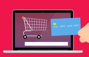 An illustration of a credit card and a shopping cart on a laptop screen.