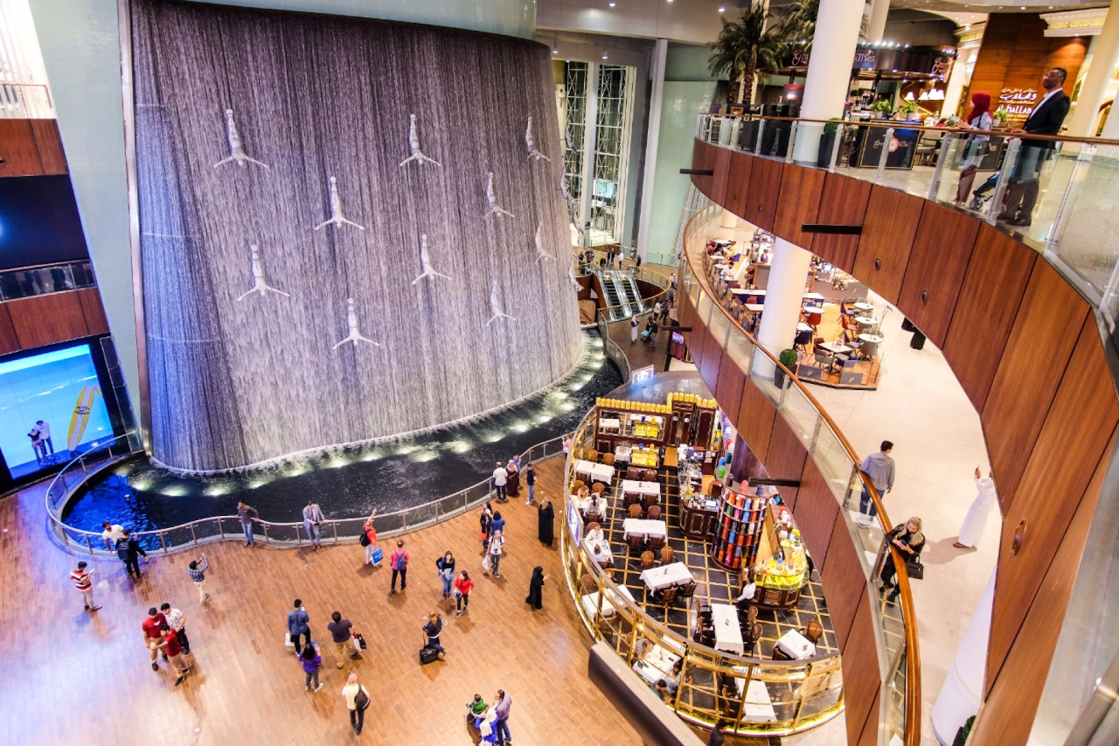 Dubai, UAE - March, 2019: A fountain or waterfall with  Silver Human Diver Sculpture figures inside Dubai Mall 