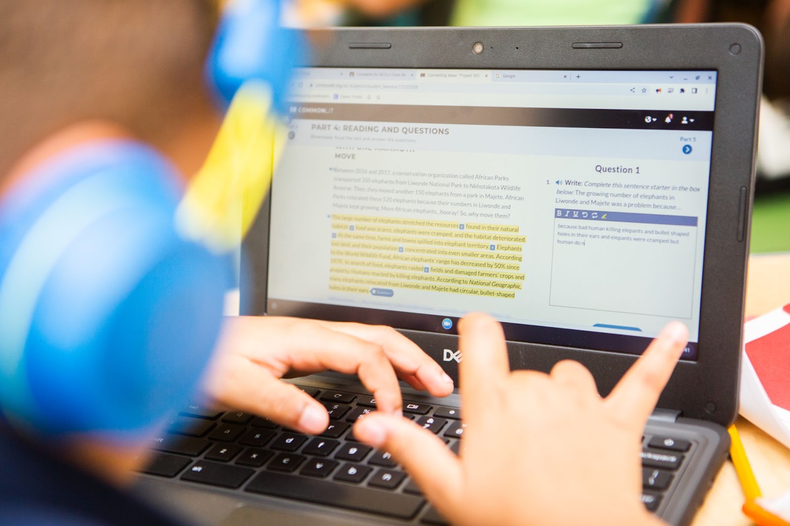 Computer screen with reading and writing lesson and student’s fingers on keyboard