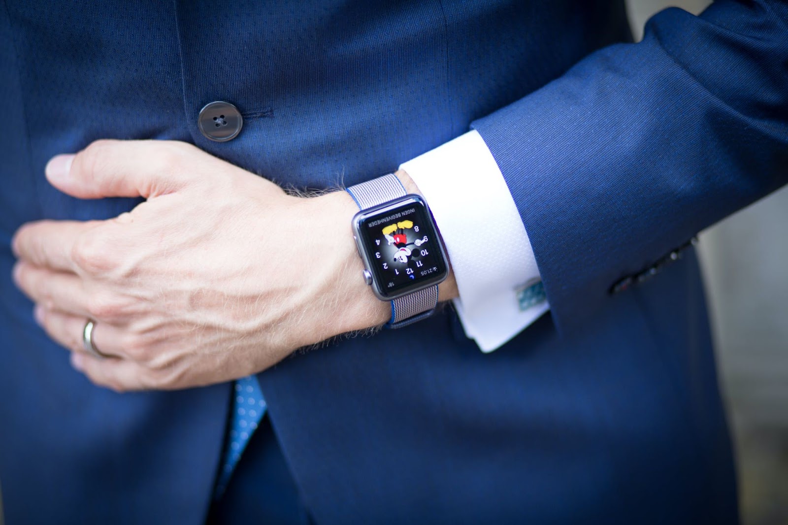A man in a blue suit wearing an Apple watch 