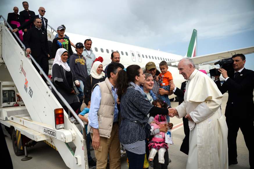 Pope Francis welcomes a group of Syrian refugees after landing at Ciampino airport in Rome following a visit at the Moria refugee camp on April 16, 2016 in the Greek island of Lesbos. Twelve Syrian refugees were accompanying Pope Francis on his return flight to Rome after his visit to Lesbos on Saturday and will be housed in the Vatican, the Holy See said. Pope Francis, Orthodox Patriarch Bartholomew and Archbishop of Athens and All Greece Ieronymos II visit Lesbos today to turn the spotlight on Europe's controversial deal with Turkey to end an unprecedented refugee crisis.  AFP PHOTO POOL / FILIPPO MONTEFORTE / AFP PHOTO / POOL / FILIPPO MONTEFORTE