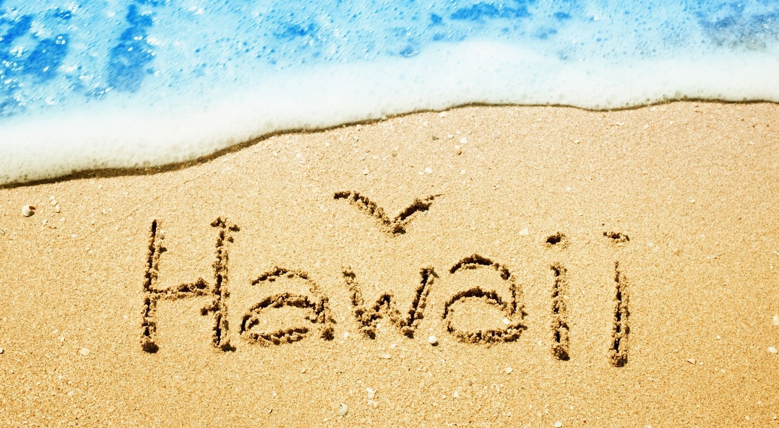 image of Hawaii written in the sand with ocean foam