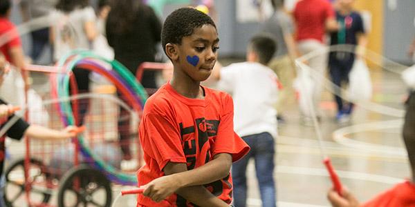 African American boy jumping rope in a gym with other kids