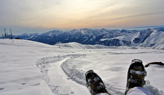 Person sitting in snow amongst mountains