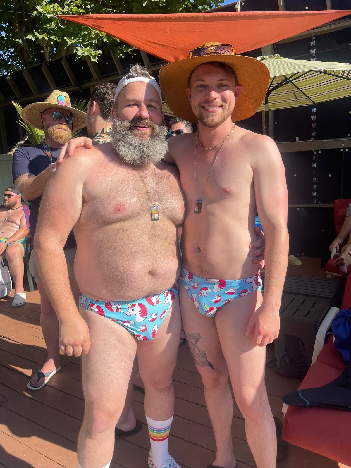 two gay male bears wearing unicorn speedos outside at lazy bar week 2023