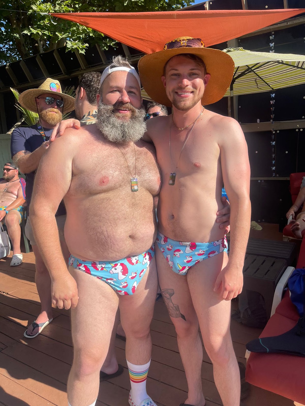 two gay male bears wearing unicorn speedos outside at lazy bar week 2023