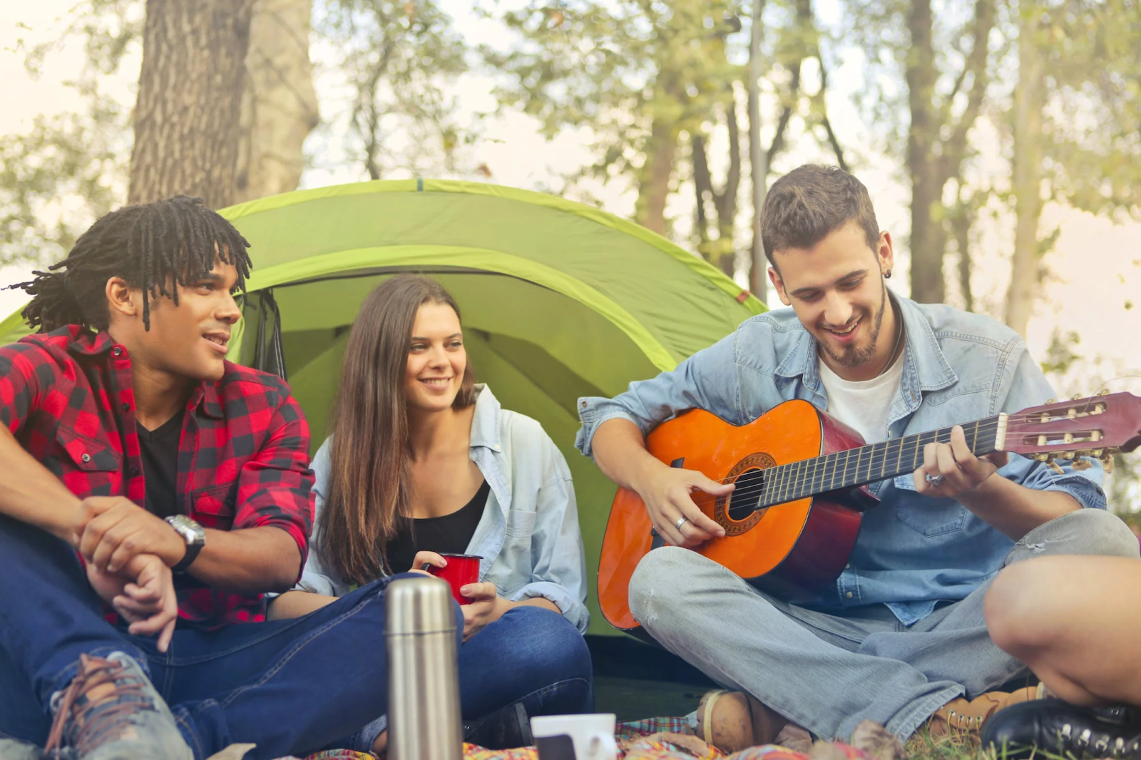 A group of people sitting in a tent playing guitar

Description automatically generated with medium confidence