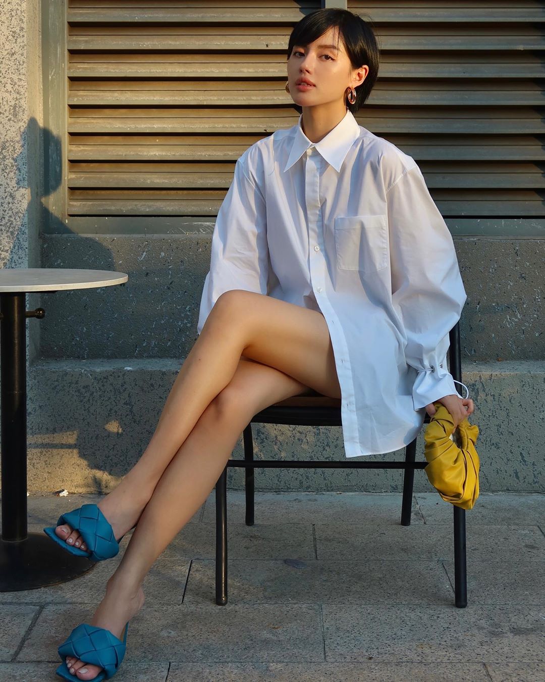 Khánh Linh mang giày mules mũi vuông màu xanh, mặc áo sơ mi trắng oversized