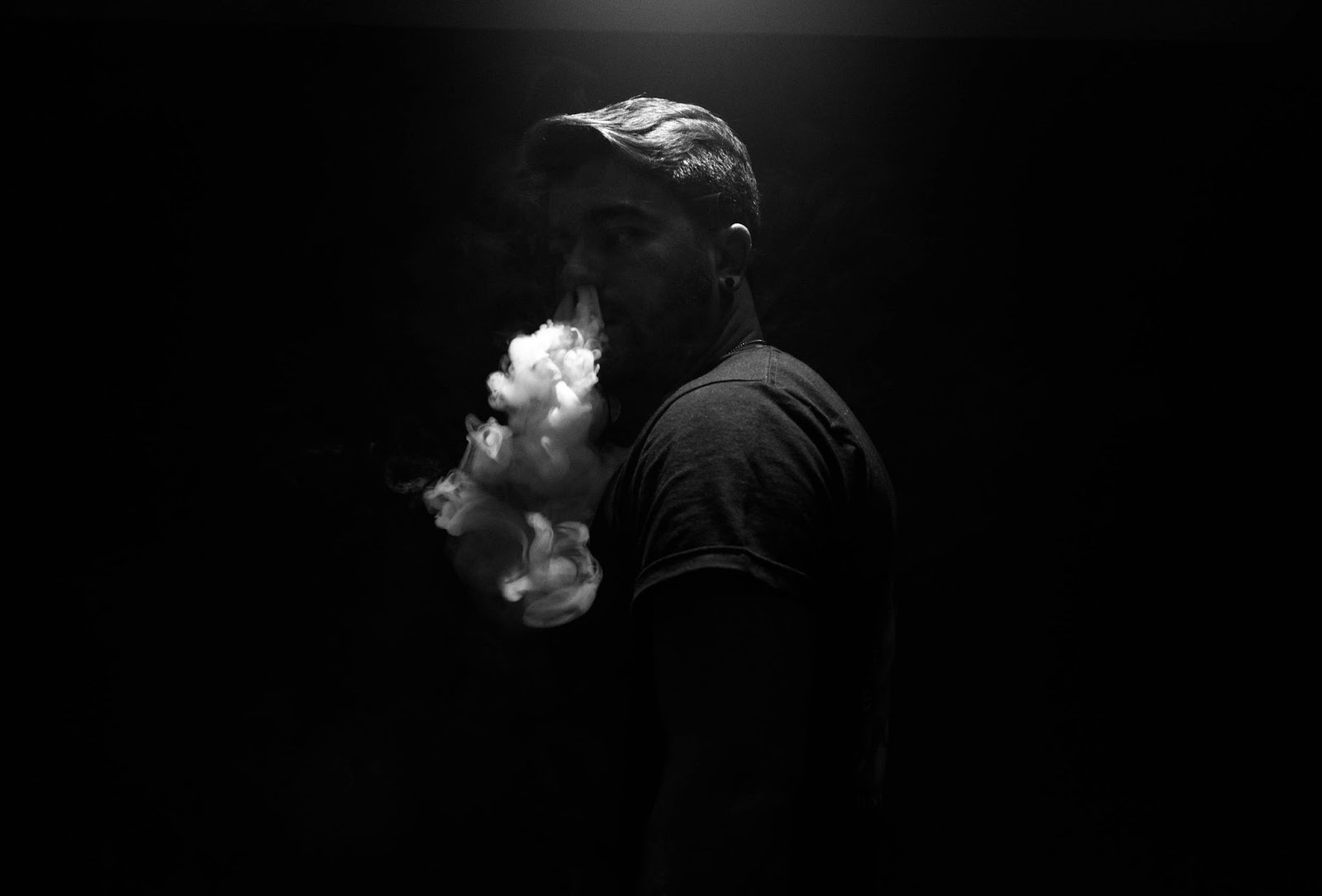 A man black and white blowing out vapor