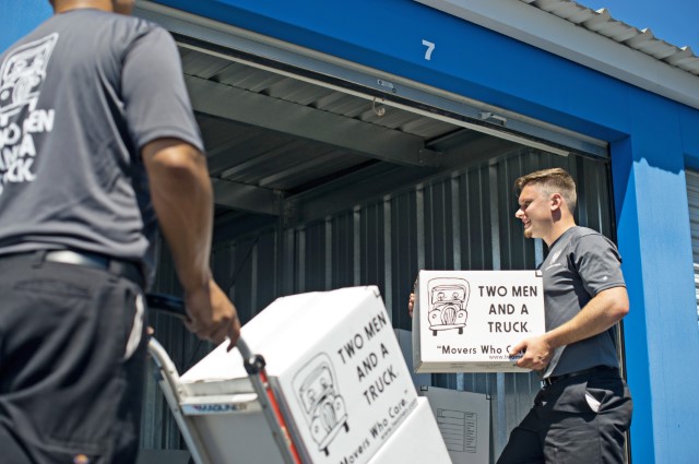 Two men and a truck employees putting boxes into a storage unit