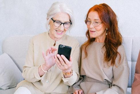 A couple of women sitting on a couch and looking at a cell phone

Description automatically generated with low confidence