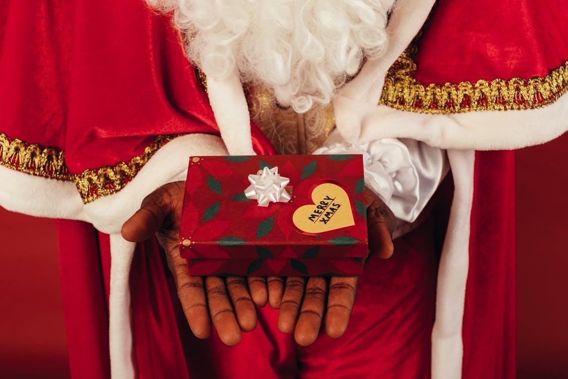 Person Wearing Santa Claus Outfit While Holding Christmas Gift