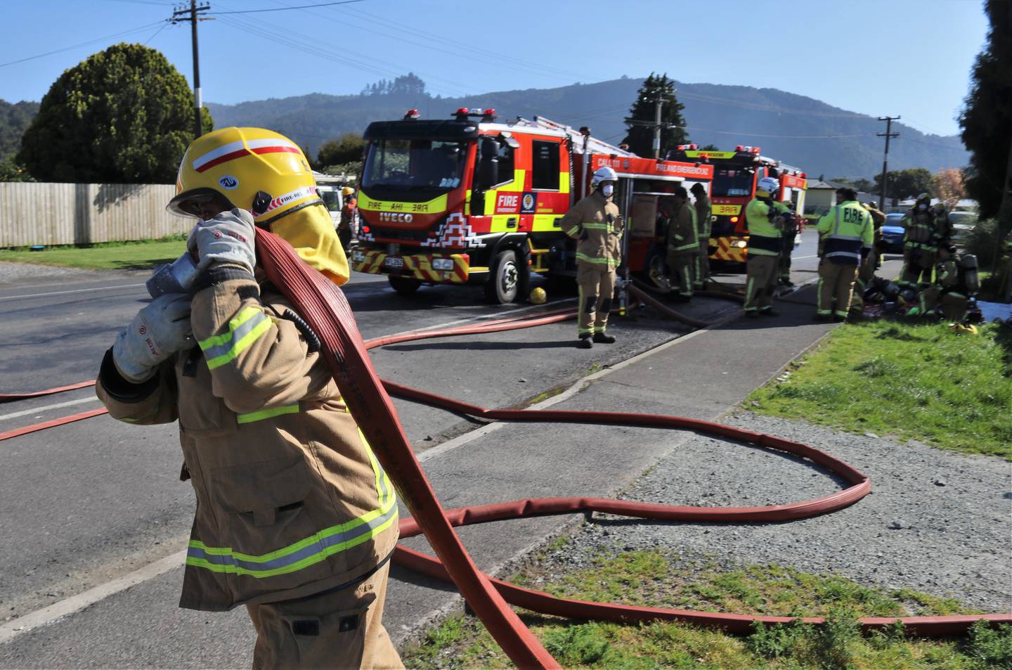 A volunteer firefighter packs up a hose after a house fire on Ōtiria Rd in Moerewa. Photo / Peter de Graaf 