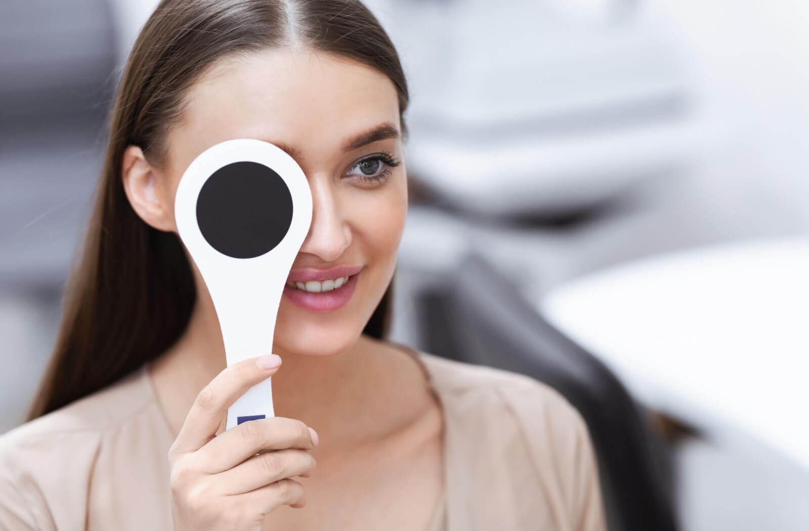 A woman in an optometrist's office her right eye is being covered by a medical instrument held to check her vision.