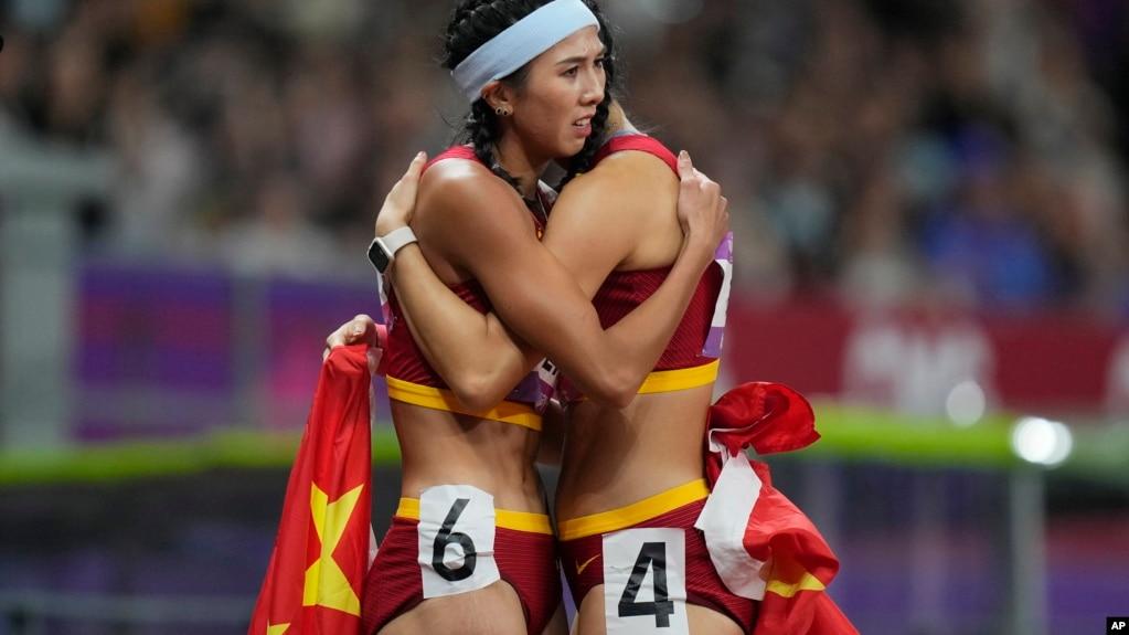 2023年10月1日中国杭州第19届亚运会女子100米栏决赛结束后,中国金牌得主林雨薇(左)拥抱中国选手吴燕妮 (美联社照片)