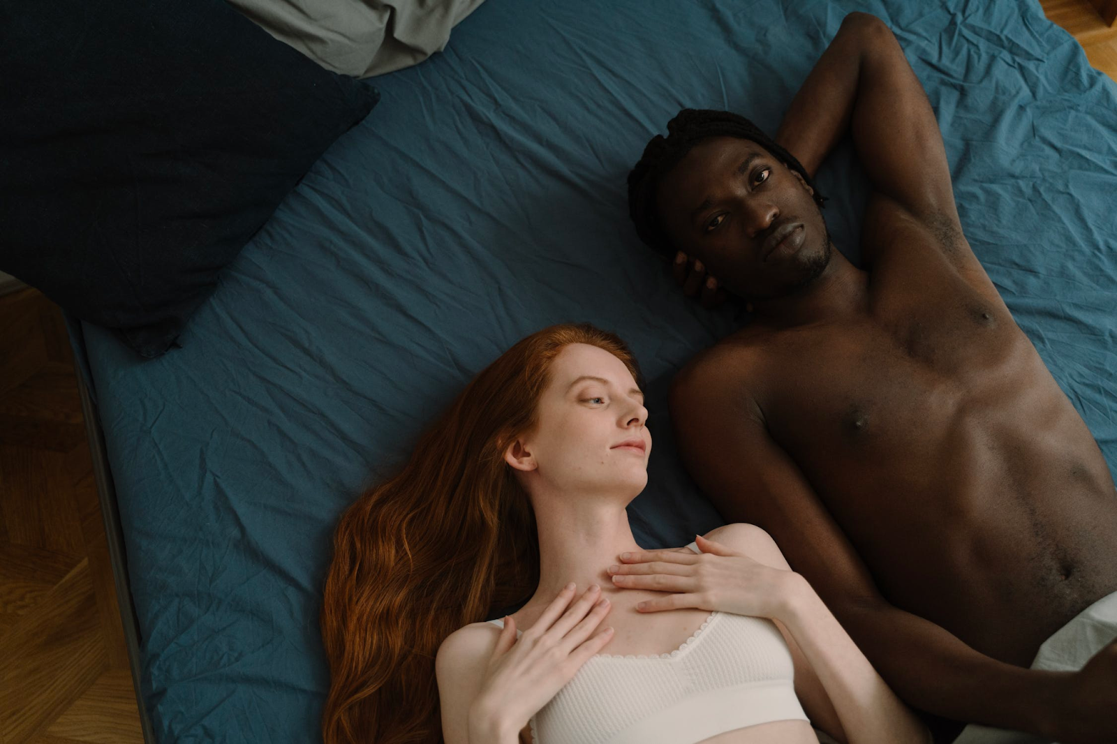 A man and woman laying down on a blue bed