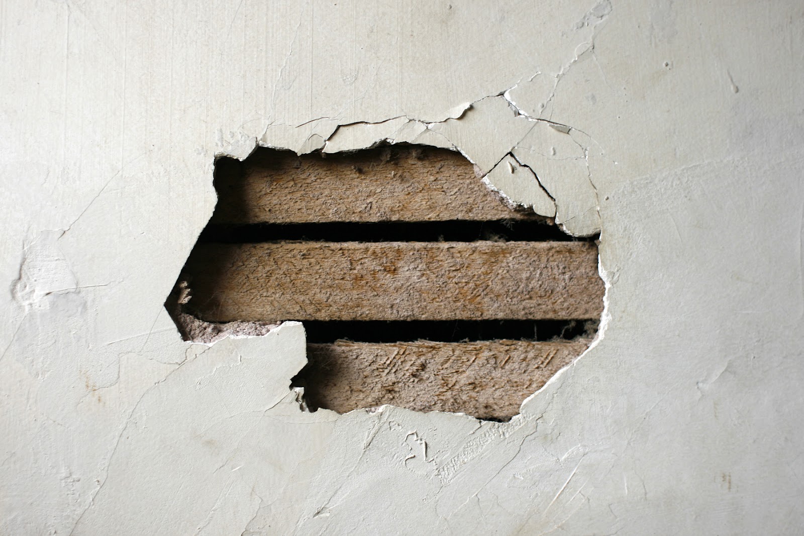Imagem mostra forro de gesso quebrado, mostrando a madeira por trás da parede. 