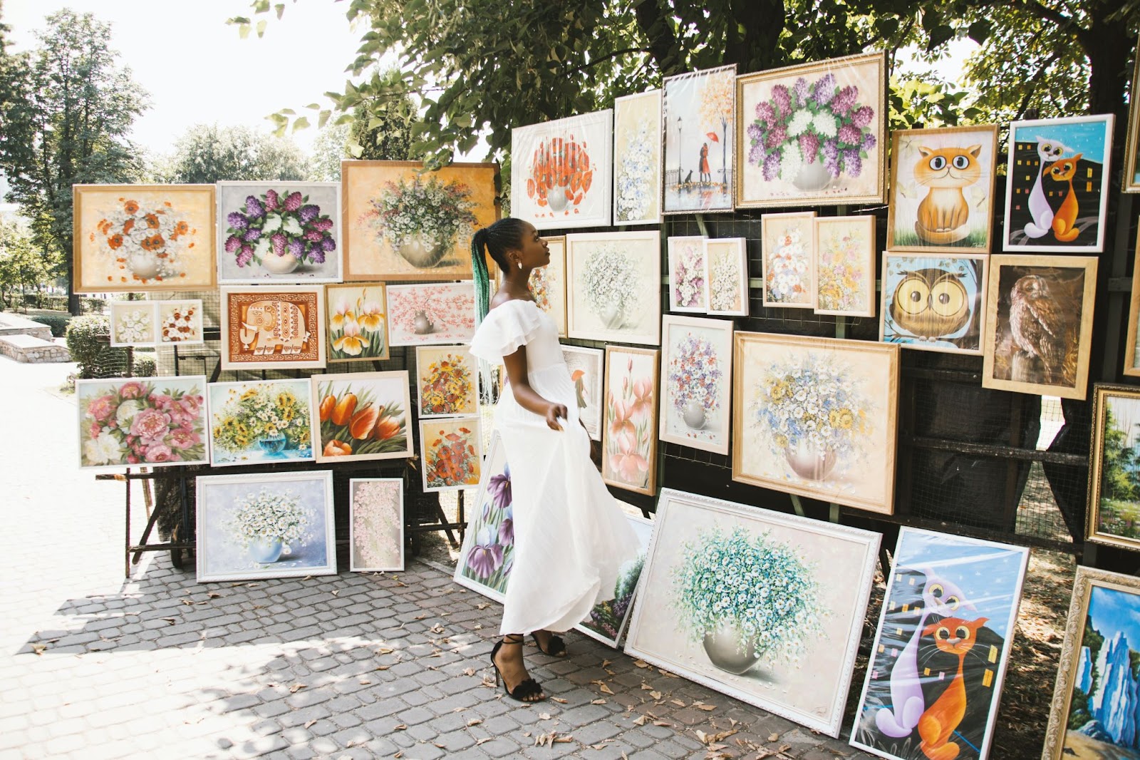 Woman in white looking at a range of artwork