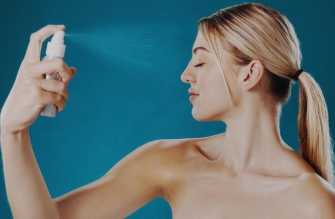 một người đang xịt cồn ethanol lên da mặt