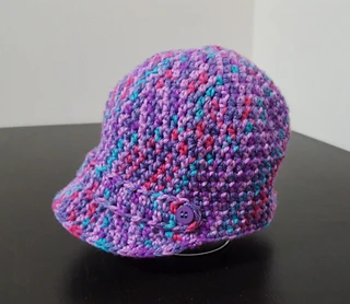 purple, pink and blue newsboy cap on wooden table