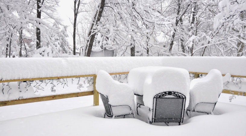 Summer patio furniture under a few feet of snow