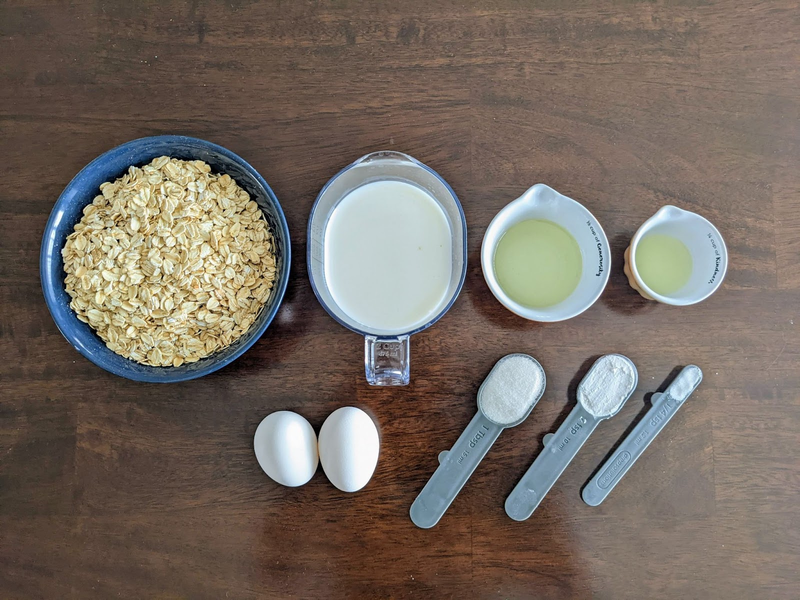 waffle ingredients including oats in a bowl next to measuring cups and eggs 