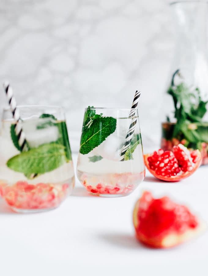 Pomegranate mint water in a glass with a black striped straw