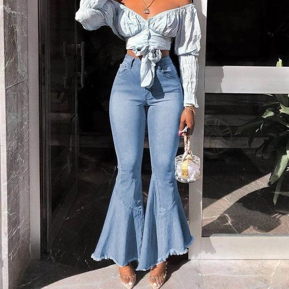 a lady wearing cropped bell-bottoms with a sky blue top and a mini bag