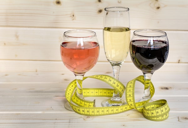Various types of wine placed on a wooden surface, with a tape measure surrounding the glass