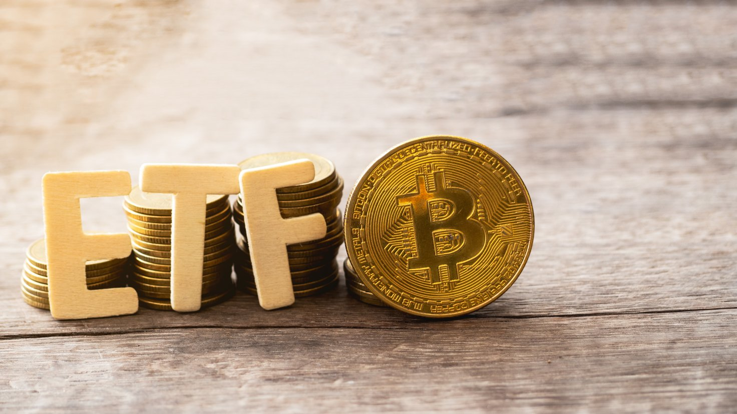 Physical Bitcoin tokens and wooden ETF letters combined for blockchain trends article.