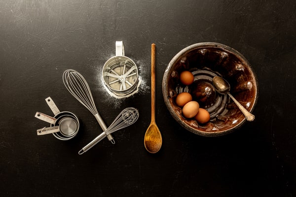 Baking tools used in making a bundt cake: measuring cups, bundt pan, wooden spatula, sifter, and wire whisk