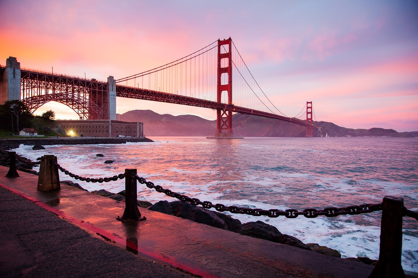 red golden gate bridge monument in san francisco with fenced path in foreground seen during sunset