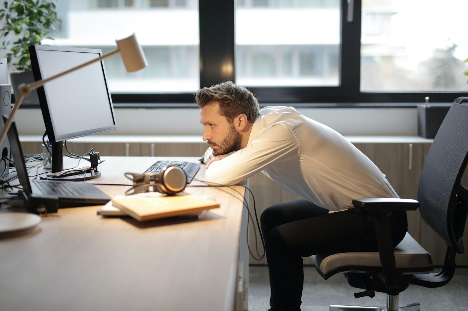 A professional slouching at his executive desk, which can result in a host of physical problems.