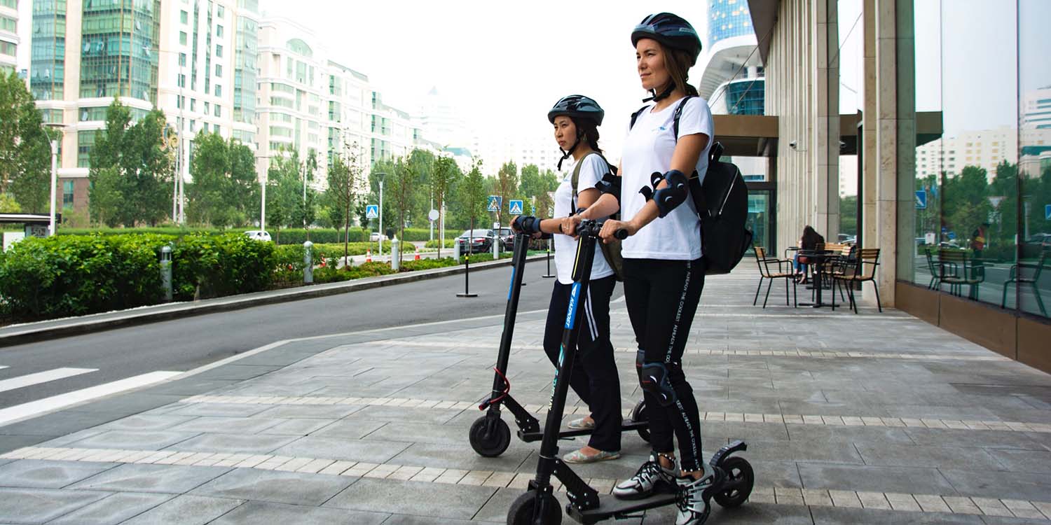 Two women riding electric scooters (escooters)