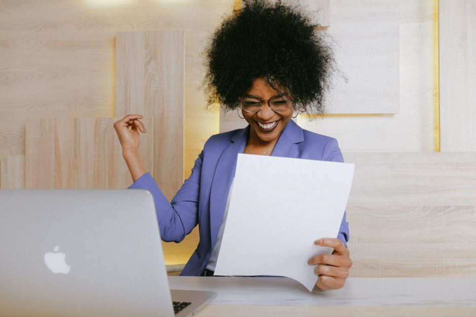 A happy business owner at a computer, smiling because she has put business systems in place.