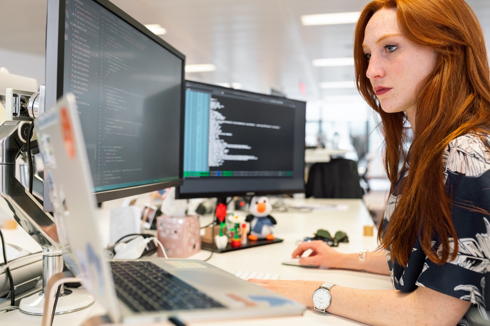 woman working in front of three screens