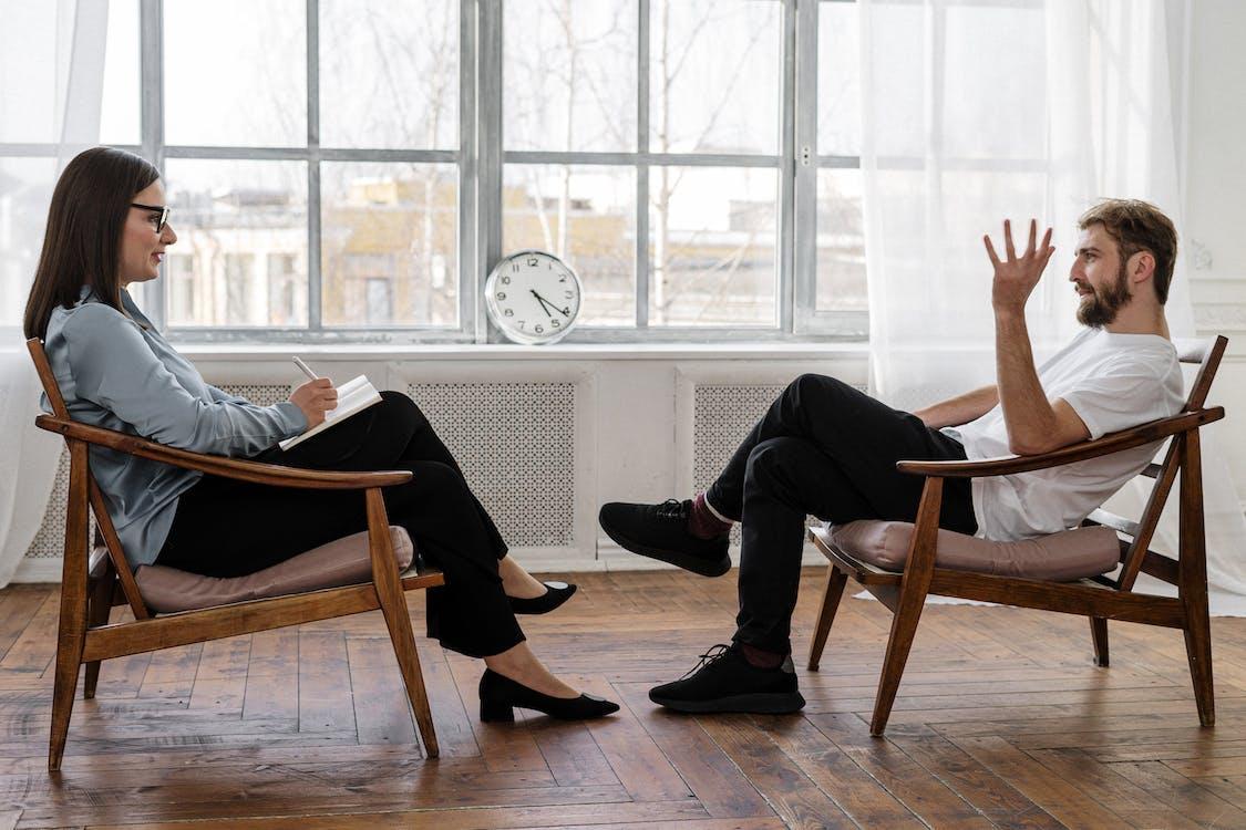 Free Person in Black Pants and Black Shoes Sitting on Brown Wooden Chair Stock Photo