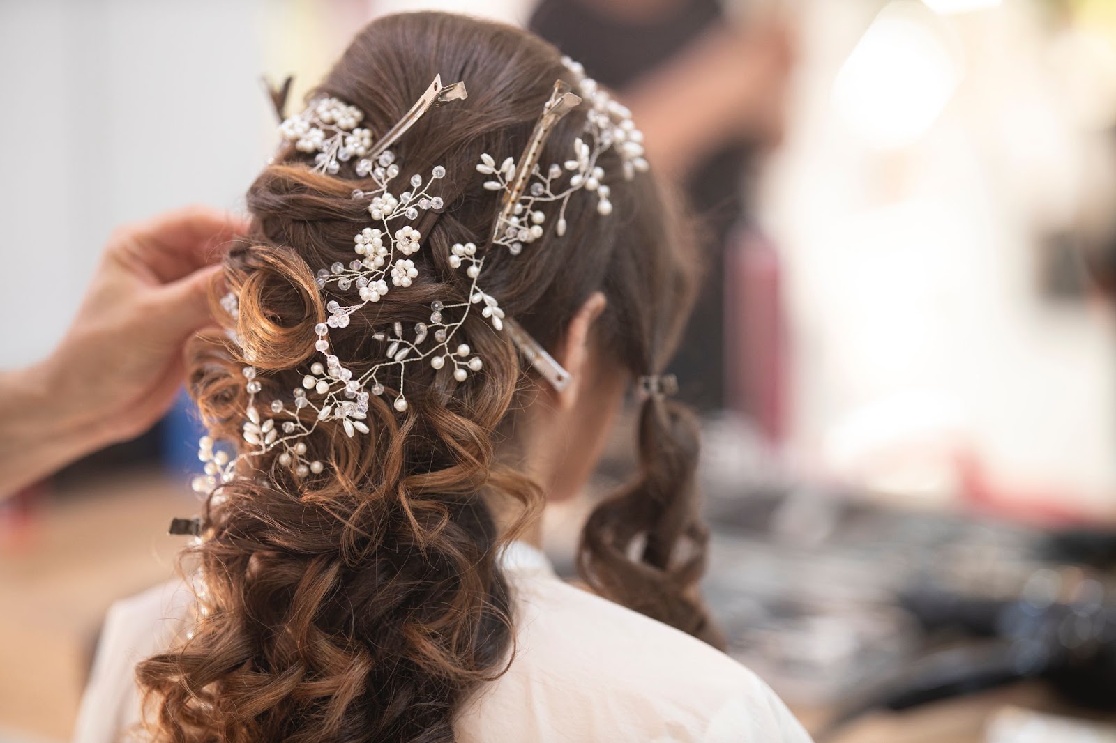 a bridal updo with hair jewelry and curls being pinned up by a kelowna hair stylist