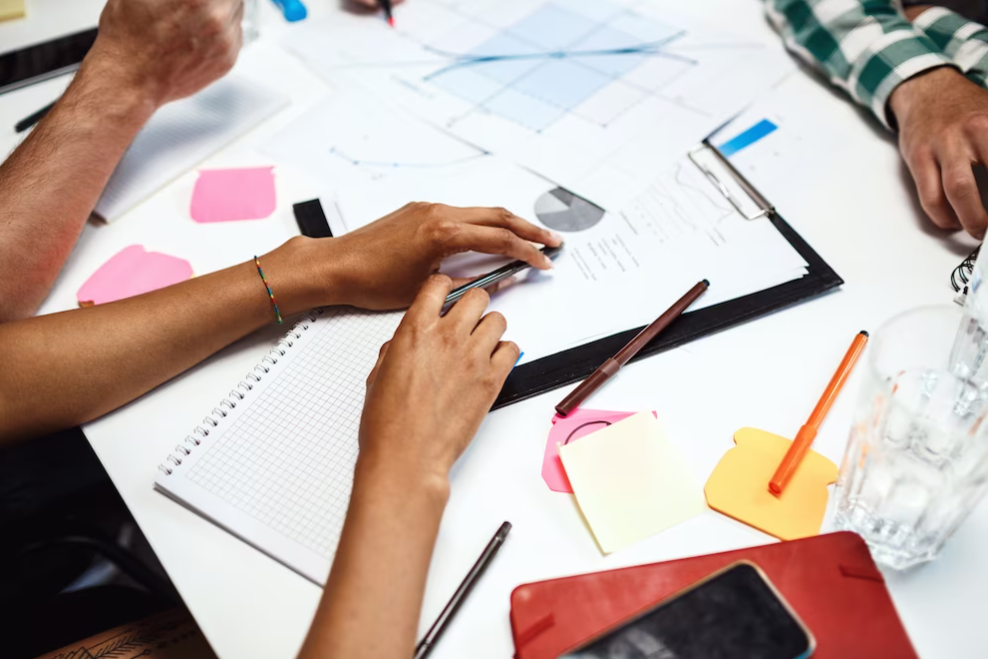 people's hands on desk with business papers