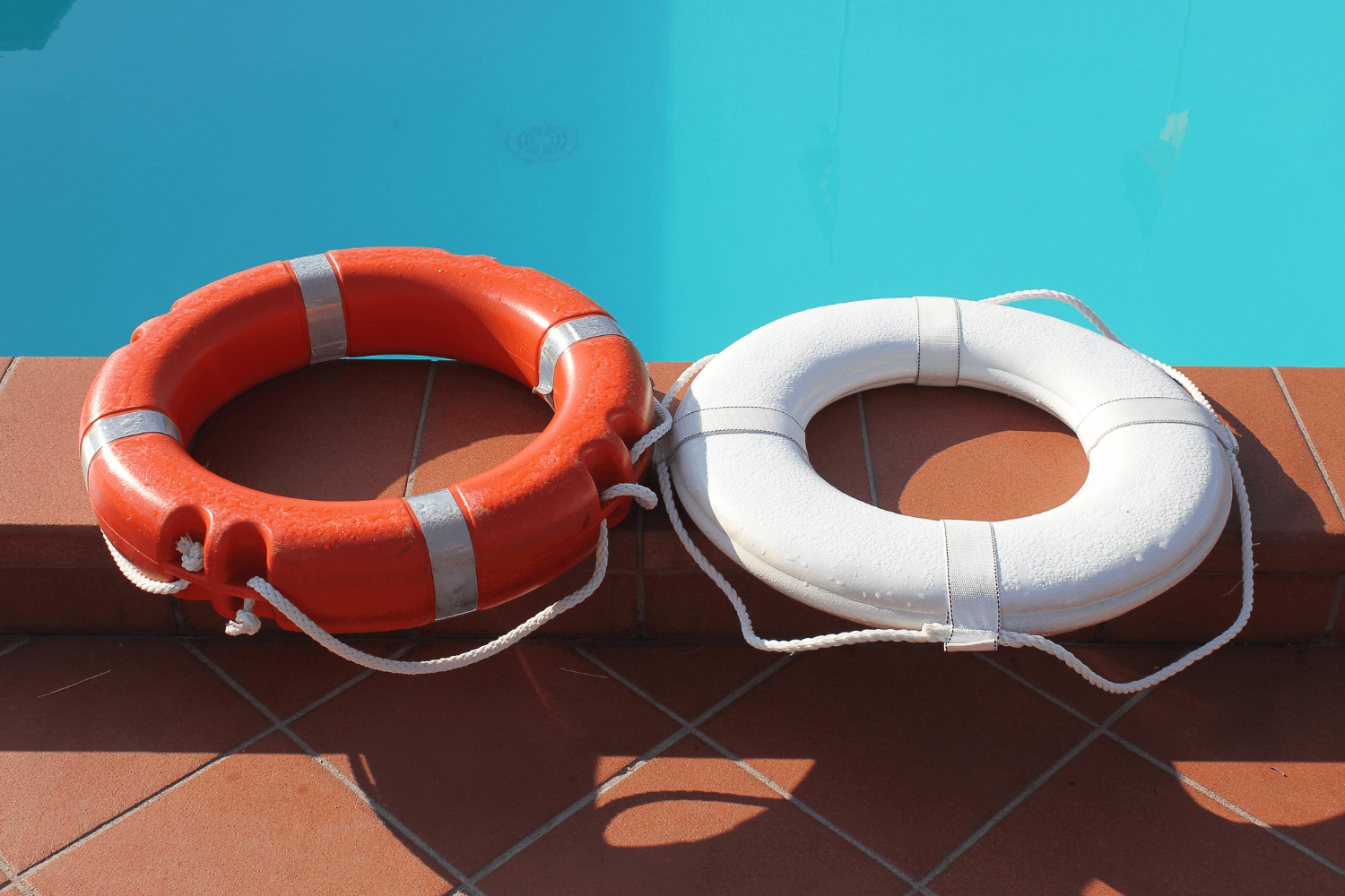 White and orange life saving buoys sitting poolside