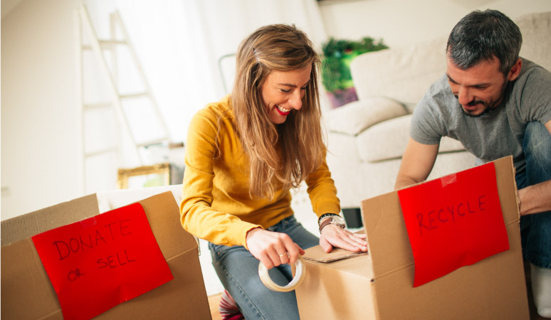 A couple taping up boxes labeled "Donate or Sell" and "Recycle"
