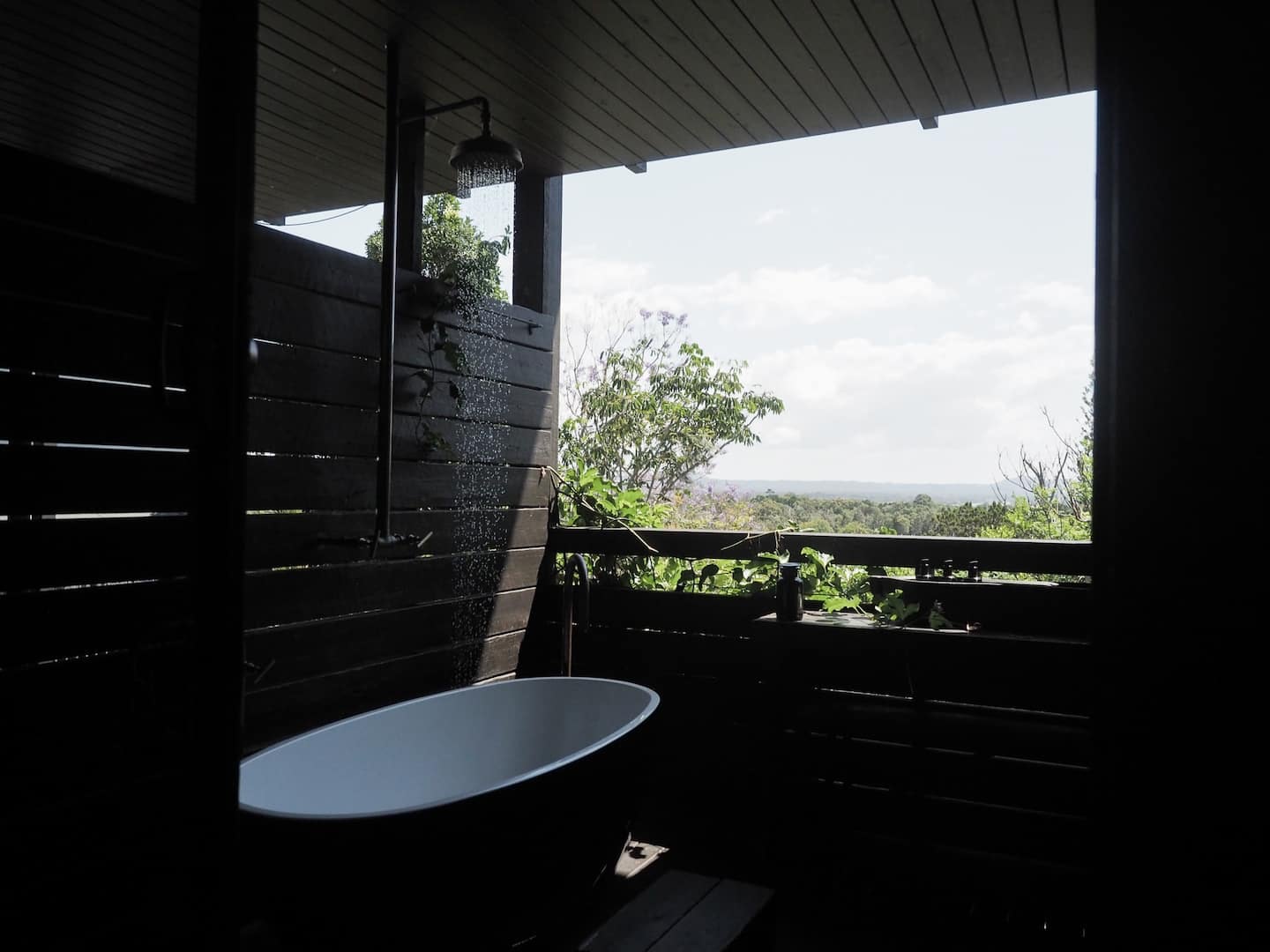 a bath tub on an all black verandah with views of the hills