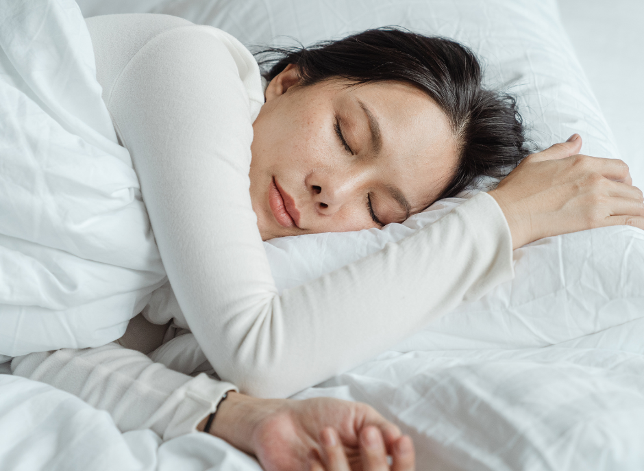 Woman sleeping peacefully on a white pillow and white bedding.