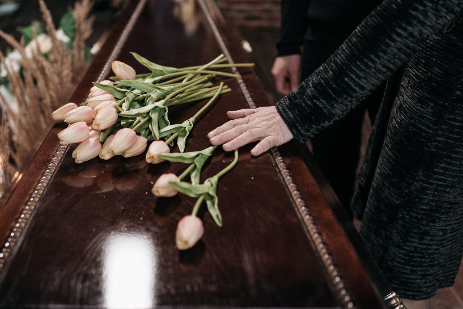 Mão e flores em cima de um caixão.